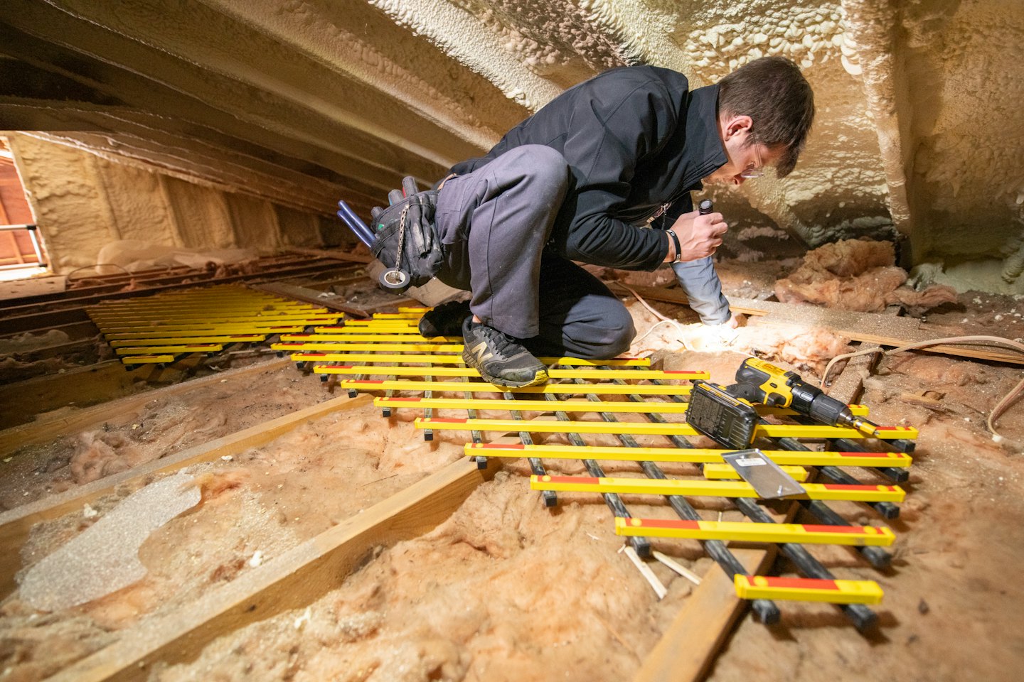 Man works on heating system in dusty attic.
